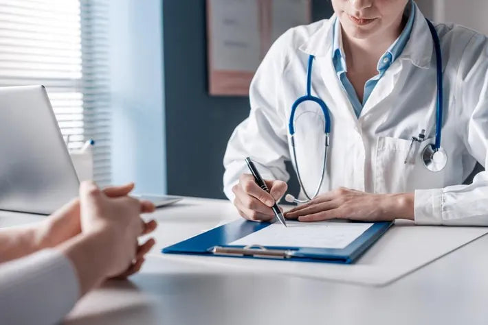 Healthcare professional in a white coat taking notes during a patient consultation.